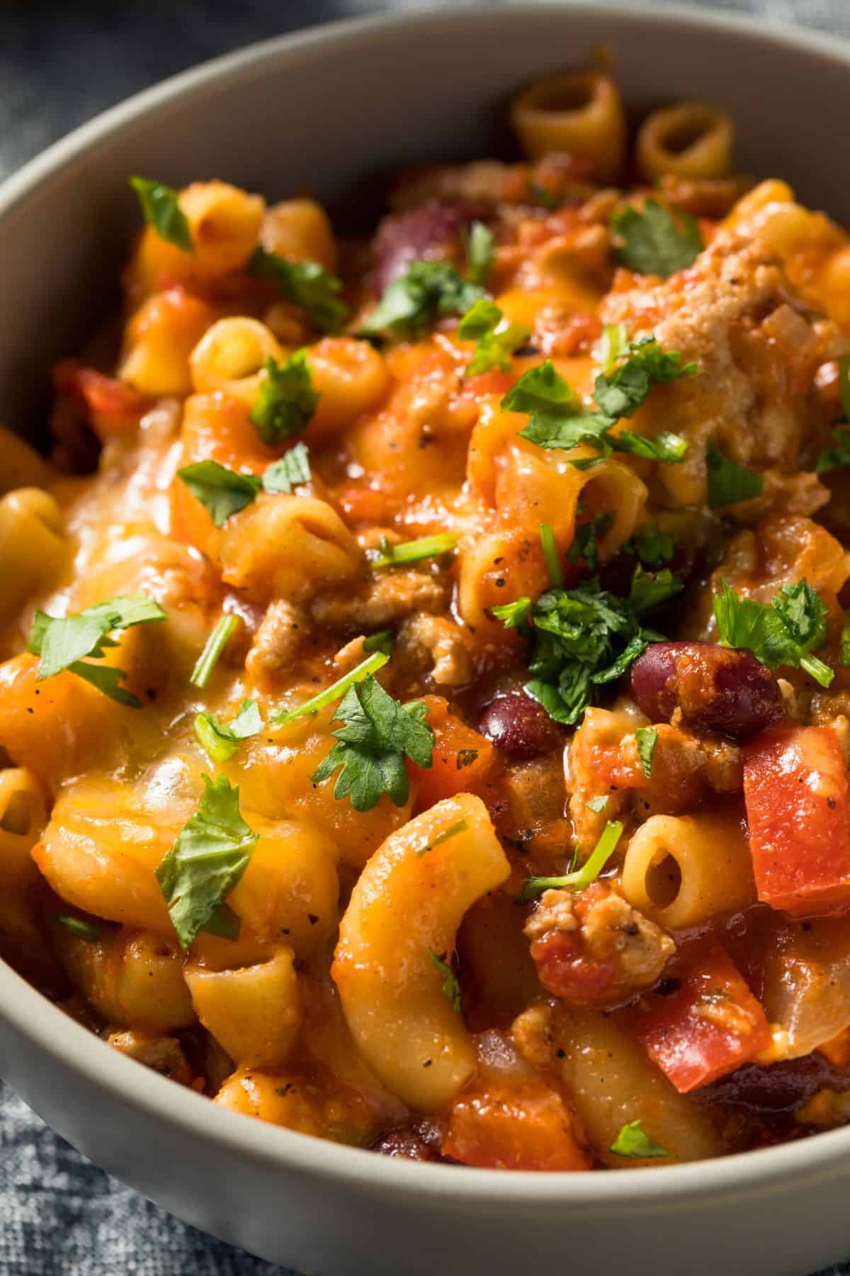Close up of a bowl of cheesy turkey chili mac ready to be devoured.